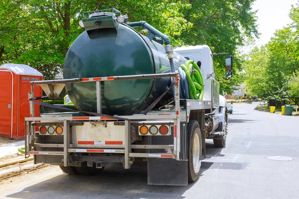 Vacuum waste truck on the cleaning process portable bio toilet cabins at the construction