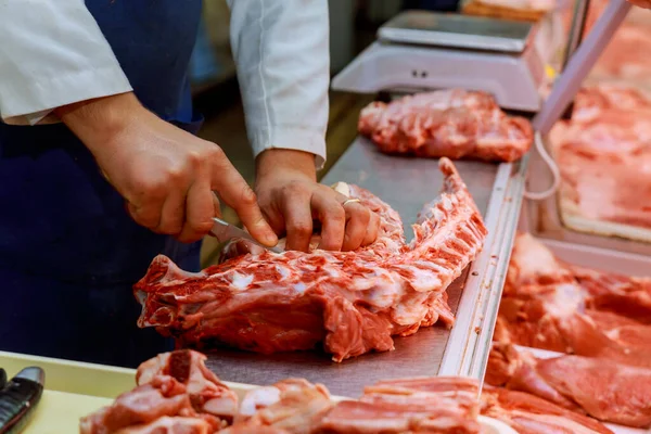 店内ではカウンターナイフで生肉の切り身を切る肉屋の手 — ストック写真