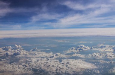 Pencereden gökyüzünü görmek için bulutların üzerinde uçan bir uçak