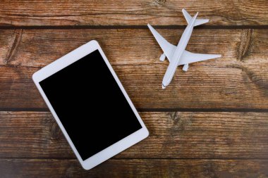 Tahta masa arkası seyahat konseptinde dijital tablet uçak modeli uçağıyla yaz tatili