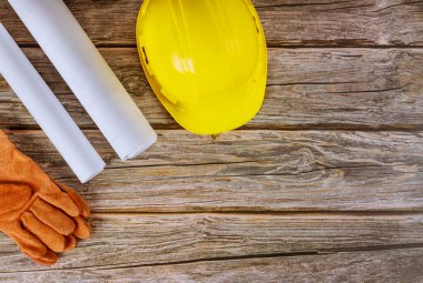 Mühendislik bürosu inşaatında çalışan mimarların planları. Sarı kaskın güvenlik eldivenleri.