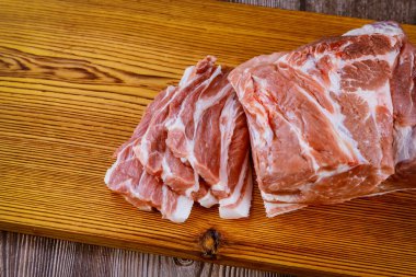 Tahtada pişmeye hazır taze domuz eti dilimleri.