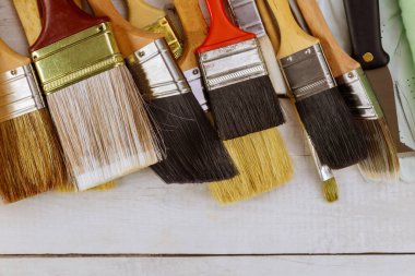 Çeşitli boya aletleri beyaz tahta masa arka planında evi yeniliyor.
