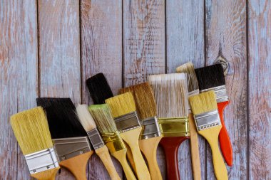 Boyacı masa tamiri, yenileme, ahşap arka planda farklı boylarda boya fırçaları.