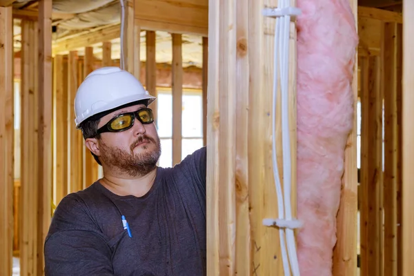 Construction worker thermally insulating insulation layer under house with glass wool soft focus