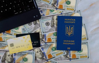 Para olarak yüz Amerikan doları Ukrayna pasaportunda kredi kartıyla online bilet satın alan bir dizüstü bilgisayar.