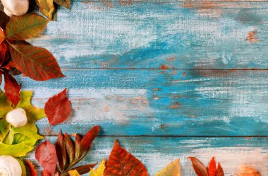 Düşen akçaağaç yapraklarından kalma eski ahşap masa kenarı Şükran Günü sonbahar arka planında.