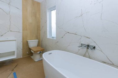 Yeni evde banyo küveti ve klozet kapağı olan modern bir banyo..