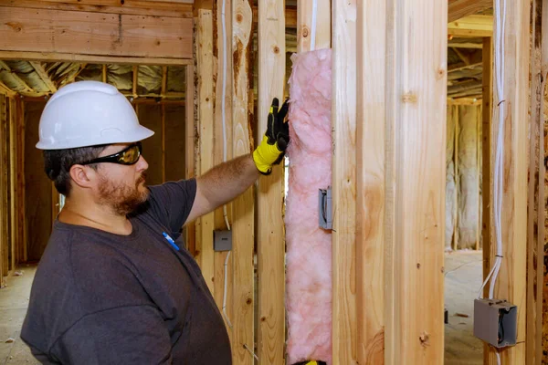 Construction worker installing thermal insulation layer under the wall using mineral wool with fiberglass cold soft focus