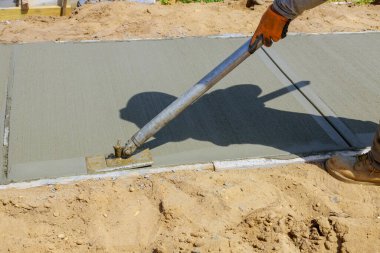 İnşaat müteahhiti kaldırım için şamandıra kullanırken beton alçıya alan işçiler.