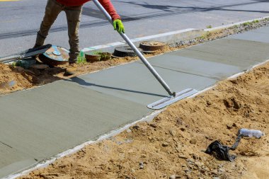 Laying down new sidewalk in wet concrete on freshly poured sidewalks clipart
