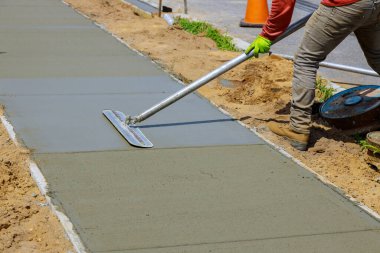 İnşaat ustası perdeli bir palto inşa ediyor. İşçi yeni beton bir kaldırımı yüzdürüyor.