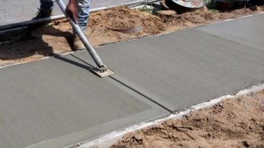 İşçiler yeni çimento kenarı üzerinde beton yüzeyi bitirdiler ve pürüzsüz hale getirdiler