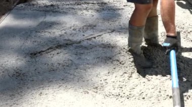 İnşaat işçisi kaldırıma el arabasıyla beton döker.