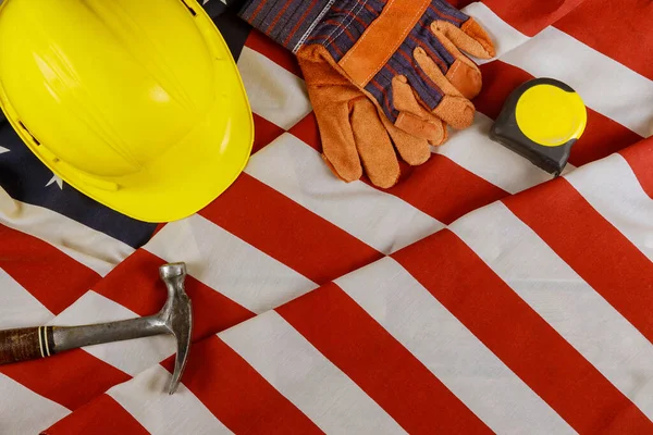 Labor day construction yellow helmet tools equipment for work happy federal holiday on over American flag background.