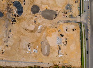 Apartman binaları olan yeni yerleşim yerlerinde çok sayıda kamyon mekanizması olan küçük bir inşaat alanının manzarası.