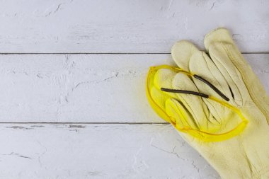 Ahşap beyaz arka planda, deri eldivenli, inşaat güvenlik gözlüklü bir mühendis olarak çalışmanın inşaat koruması.