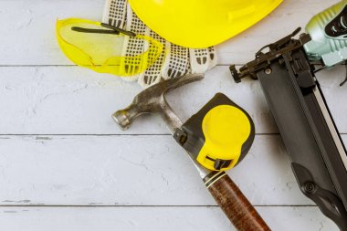 Güvenli iş giysisi hava çivi aleti pnömatik çivi tabancası eldiveni bant mezurada güvenlik gözlüğü inşaat çekici eski ahşap arka planda