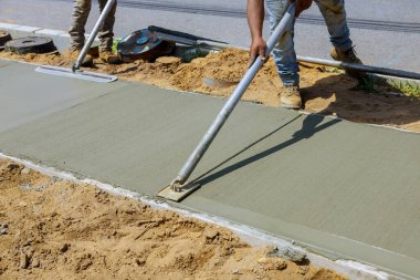 İnşaat müteahhiti kaldırım için şamandıra kullanırken beton alçıya alan işçiler.
