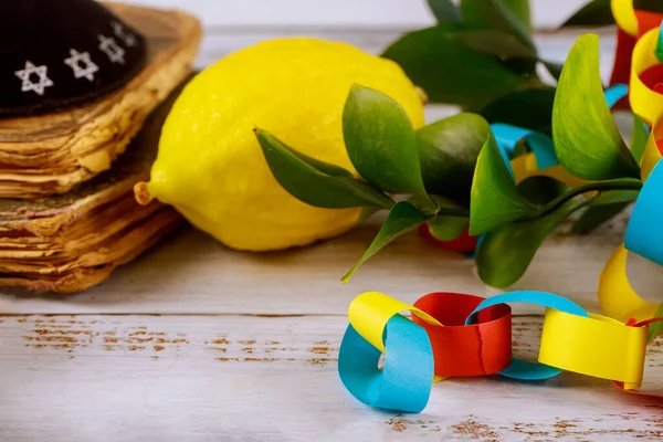 Symbols traditional Jewish religious festival over paper colorful chain garland of Sukkot praying book kippah tallit