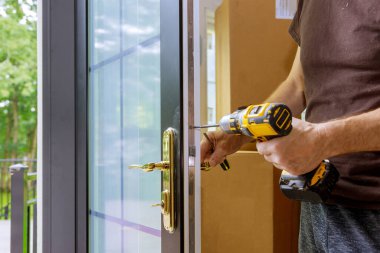 Kapı kolunu kilitle, Carpenter vidayı sıkıştır, elektrikli matkap tornavidayla, yakın çekim..