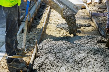 İnşaat işçisi kaldırıma çimento döktü. Kaldırıma beton döktü.