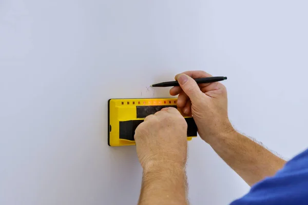 Man hand is scanning wall by uses Multi-Sense Technology to find studs more accurately through difficult surfaces.