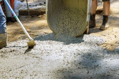 Beton karıştırıcı kamyonun beton dolu kürekleriyle yeni dökülmüş çimento el arabasının yapımı.