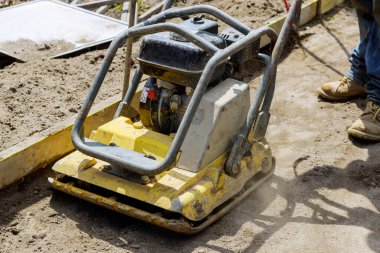 Endüstriyel bir inşaat makinesinde yeni bir kaldırımda titreşimli tamping makinesi plakası sıkıştırıcısı