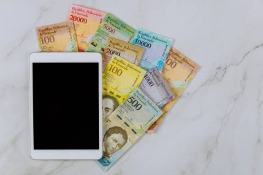 Tablet PC seri banknotlar farklı kağıt banknotlar para birimi Venezuela Bolivar masa üzerinde