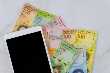 Ofis masası dijital tablet Venezuela Bolivar banknotuyla çalışıyor..