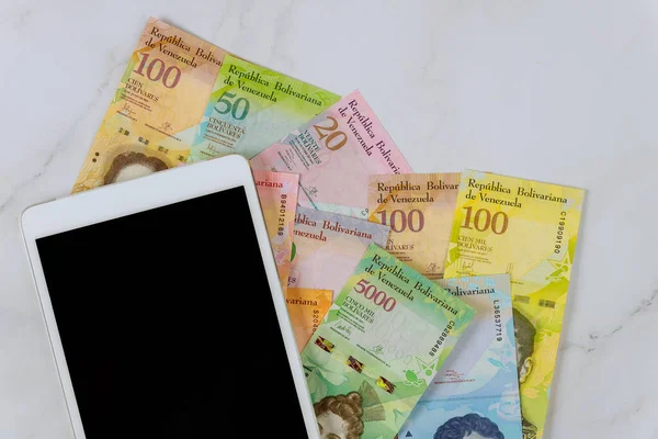 Ofis masası dijital tablet Venezuela Bolivar banknotuyla çalışıyor..