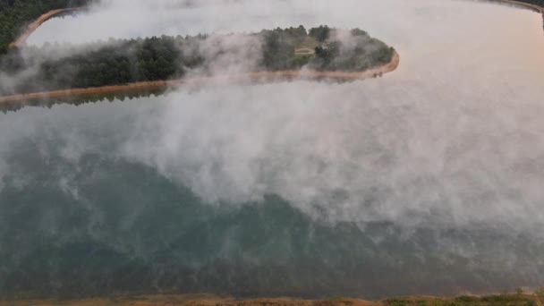 Ochtendzicht op meer met mist boven wateroppervlak en zonsopgang boven bos — Stockvideo