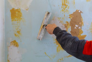 Erkek işçi duvar için macunlu alçıtaşının ilk katmanını kullanıyor.