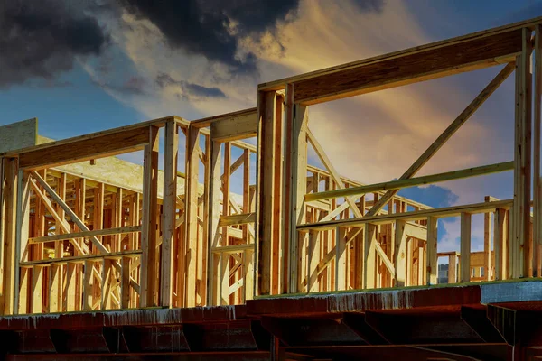 New residential construction home framing home against a dramatic sunset sky bright horizon