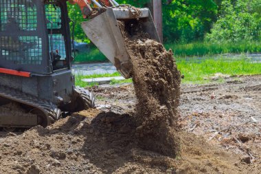 Buldozer hareket ediyor, yerdeki inşaat alanında kürekleri kullanarak zemini düzleştiriyor.