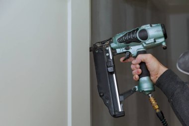 Marangoz, yeni kapıya çivi yerleştirmek için hava tabancası kullanıyor.