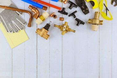 Tesisatçılar için gerekli aletler, eski ahşap arka planda bakır boru, dirsek eklemi, İngiliz anahtarı paslanmaz çelik gibi tesisat malzemelerini tamir etmeden önce ustalar tarafından hazırlandı.