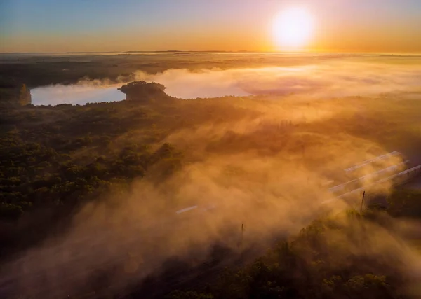 太陽の光で美しい幻想的な霧の湖は ツリー劇的なカラフルな風景を介してビーム — ストック写真