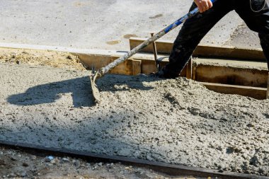 Kaldırımın önündeki çimento yeni kaldırımda inşaat işçisi beton yüzeyi altında yeni bir bina.
