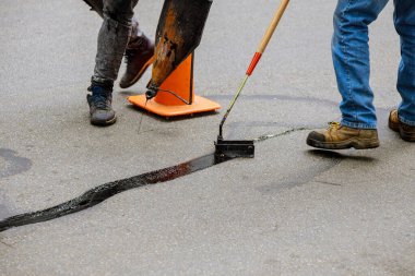 İşçide yol yüzeyi yenileme çalışmaları, bitumen emülsiyon asfalt yüzeyi ile kaplanarak çatlakların onarımı ve kapatılması üzerinde yol yaması üzerinde çalışır..
