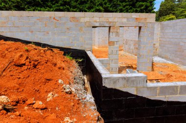 İnşaat işçileri yeni evler için zemin hazırlıyorlar, engellenmiş duvarları sergiliyorlar iş günlerinde zengin kırmızı toprak