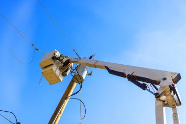 Elektrik işçileri mavi gökyüzünün altındaki kiraz toplayıcısının elektrik hatlarını tamir ediyorlar..