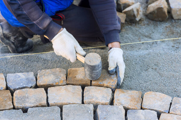 Работник аккуратно кладет камни во время строительства дорожки в жилом дворе под рабочий день