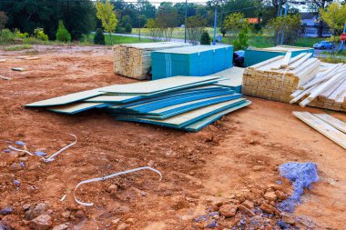 İnşaat malzemesi yığını, iş gününün erken saatlerinde huzurlu sokaklarla çevrili kir sahasında duruyor.