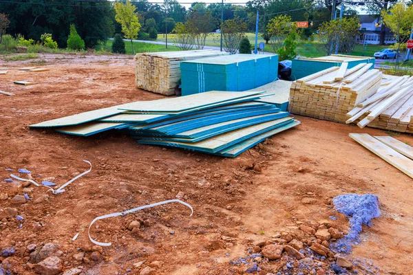 İnşaat malzemesi yığını, iş gününün erken saatlerinde huzurlu sokaklarla çevrili kir sahasında duruyor.