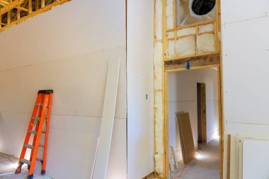 İşçiler ev yenileme çalışmalarına alçıpan döşüyorlar, iç çalışma ortamlarına inşaat detayları yerleştiriyorlar.