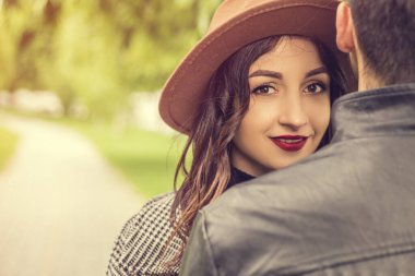 İki güzel çiftin romantik aşk hikayesi. Çekici bir erkek ve güzel bir kadın birbirlerine sarılıyorlar. Genç bir adamın omzunun üzerinden kameraya bakan kız arkadaş.. 