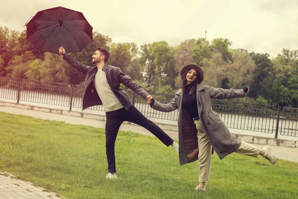 부부가 거리에서 재미있게 바람이 우산을 갑니다 이성애자들은 비오는 비행기를 간다고 — 스톡 사진
