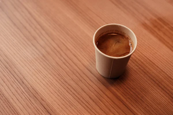 Kafedeki ahşap masada sıcak kahve ile doğal kağıt bardağın en üst görüntüsü. Amerikano, espresso, ristreto ya da diğer kahve çeşitleriyle tek kullanımlık çevre dostu organik bambu bardakları. Boşluk ve maketi kopyala.